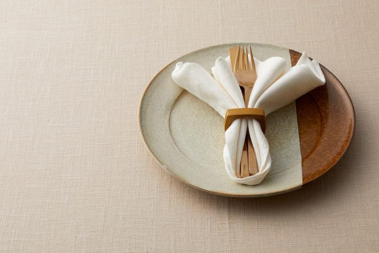 Cubiertos de madera y servilleta cogidos dentro del servilletero, presentación artística.