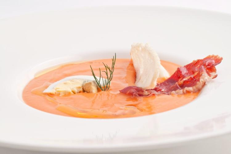 Un plato de salmorejo cordobés servido con huevo duro y jamón serrano.