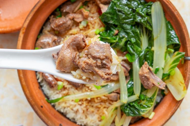 Un recipiente de cerámica con arroz y trozos de pichón escabechado.