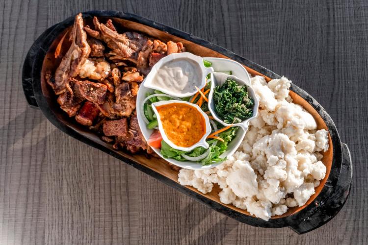 Plato suazi con carne a la parrilla, o braai, a la izquierda, pap blanco a la derecha, con verduras, ensalada y salsas en el centro.