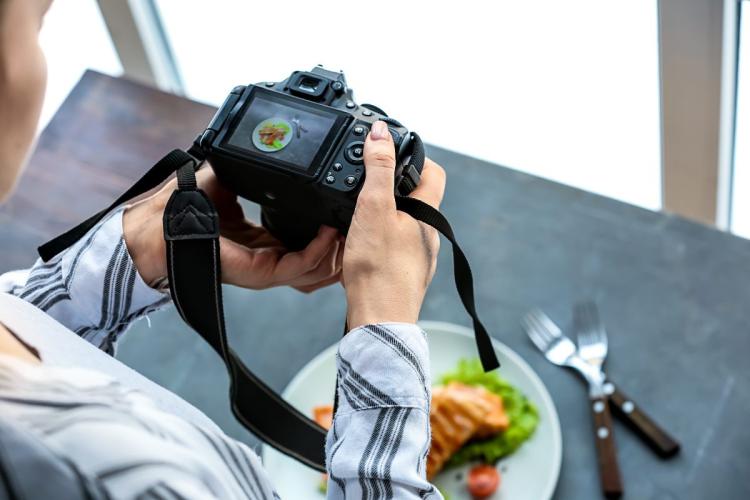 Una mujer joven sacando una fotografía de un plato de comida en un estudio profesional.