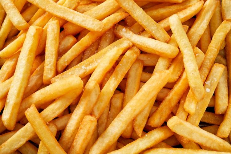 Detalle de patatas fritas clásicas, cortadas en bastoncitos, fritas congeladas..