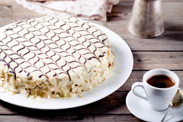 Tarta Esterhazy, un pastel húngaro de capas finas de bizcocho de nuez rellenas de crema de mantequilla y ron, cubierto con glaseado blanco decorado con dibujo de telaraña.