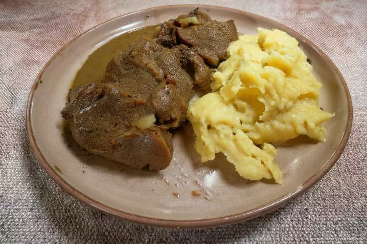 Un palto con carne guisada acompañ1ado de su salsa y puré de patata.