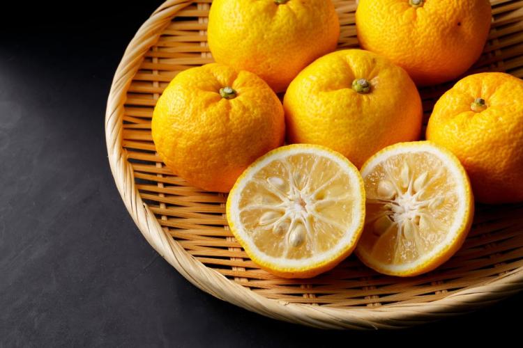 Frutos de yuzu enteros y cortados en una cesta de mimbre.