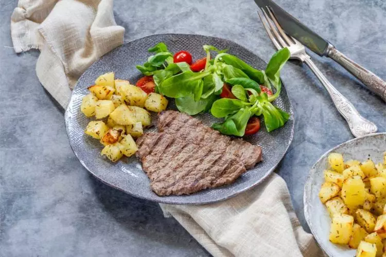 Un par de filetes al minuto con su guarnición de patatas salteadas y ensalada de tomates cherry y canónigos.