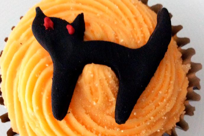 Bizcochito decorado con glaseado naranja y gato negro de chocolate.