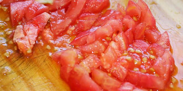 Tomate picado sobre una tabla de cortar de madera.