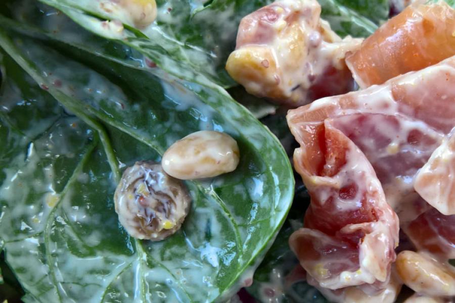 Ensalada de espinacas, piñones y pasas con jamón serrano aliñada.