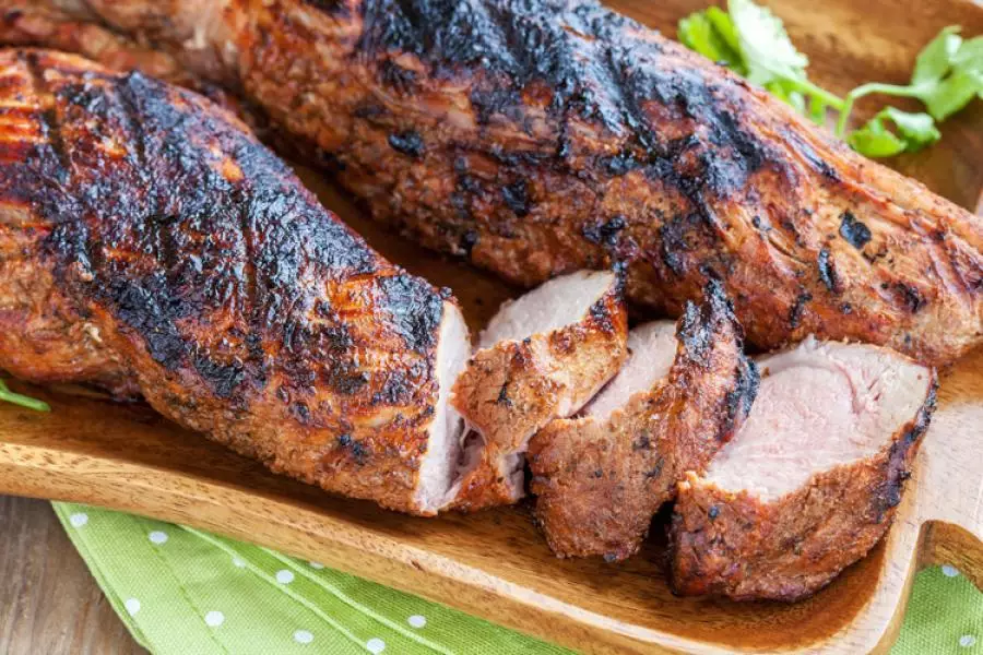 Dos trozos de solomillo de cerdo asado a la parrilla, se ha cortado algunos medallones de uno de ellos.