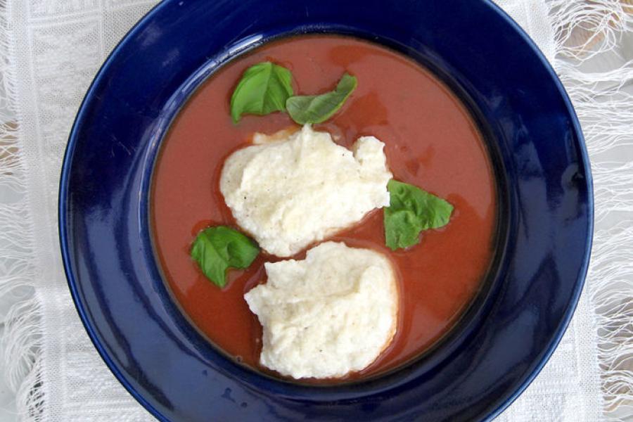 Sopa alemana de tomate decorada con queso crema y albahaca fresca.