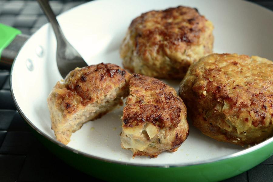 Tres albóndigas alemanas, frikadellen, en una sartén. Una de ellas partida por la mitad.