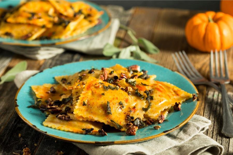 Ravioli de calabaza con salsa de salvia y nueces en un plato.