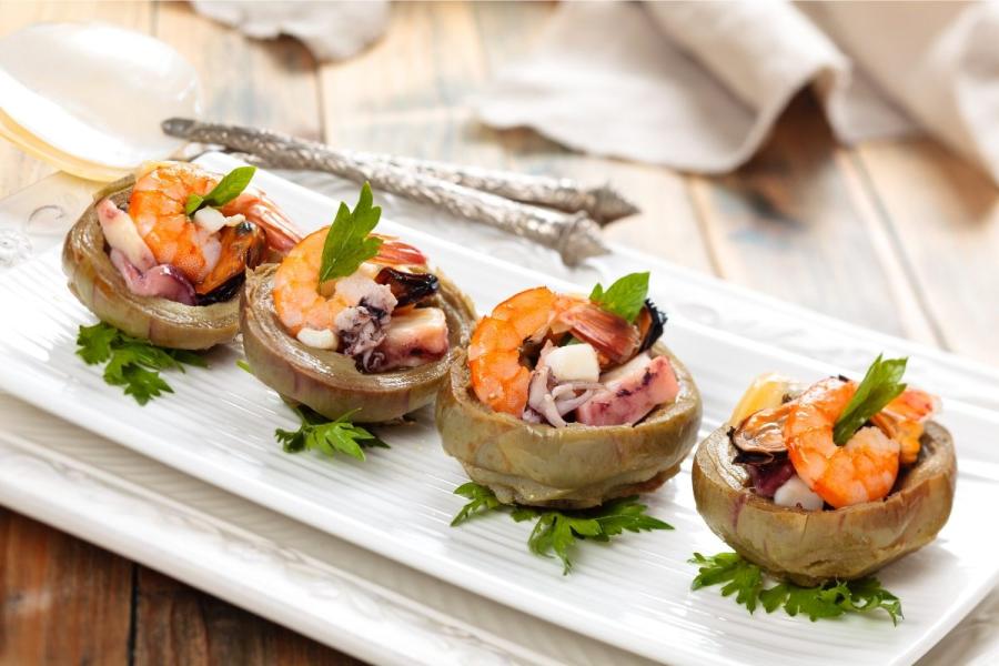 Fondos de alcachofa cocidos y rellenos sobre una tabla.