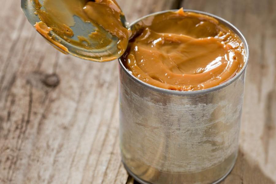 Una lata abierta con dulce de leche de leche condensada.