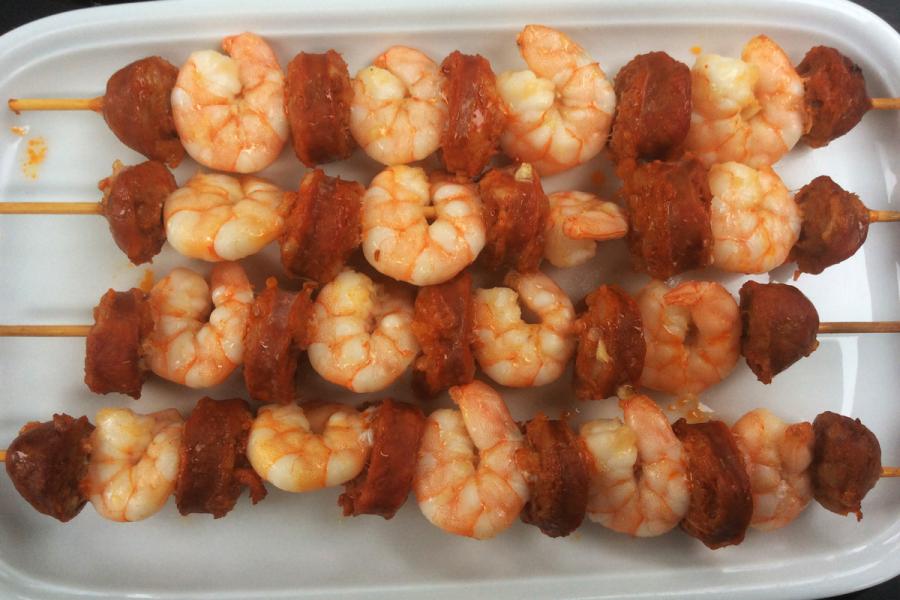 Brochetas de gambas y chorizo en una fuente de loza.