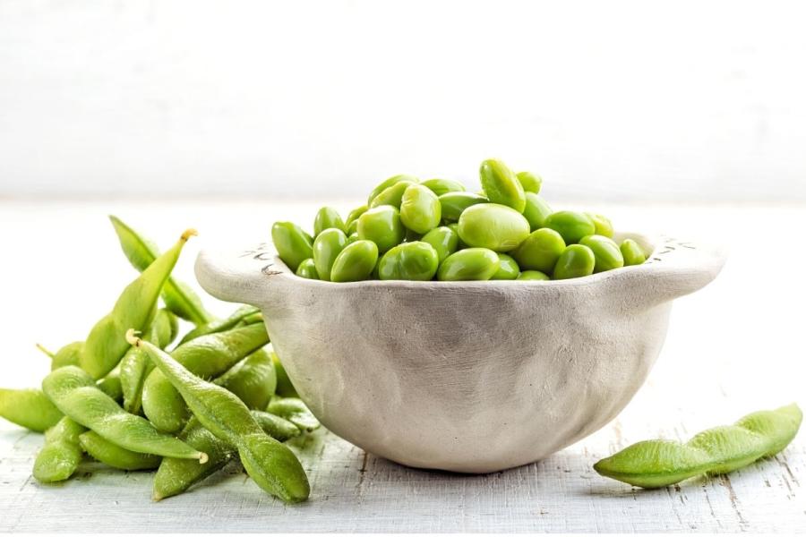 Un cuenco con edamame desgranado junto con algunas vainas enteras.