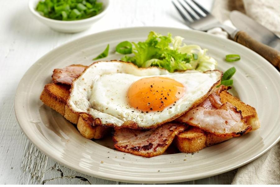 Tostada desayuno inglés con tocino frito y huevo.