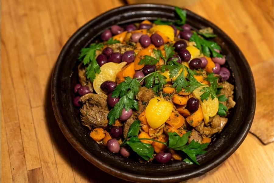 Tayín de cordero con aceitunas en el recipiente, sin la tapa.