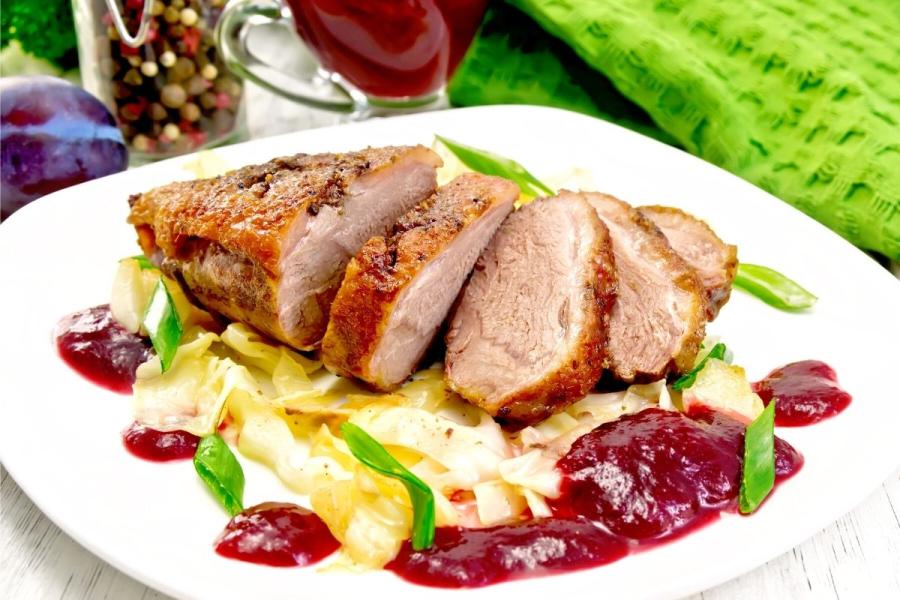 Pechuga de pato cortada en rodajas servida con salsa de ciruelas.