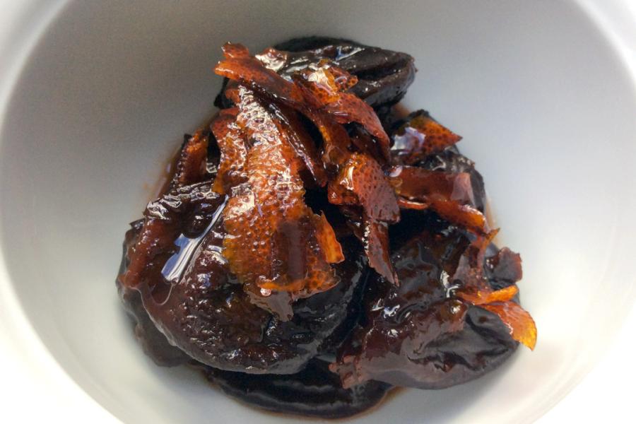 Ciruelas en almíbar al oporto con tiras de cáscara de naranja caramelizada.