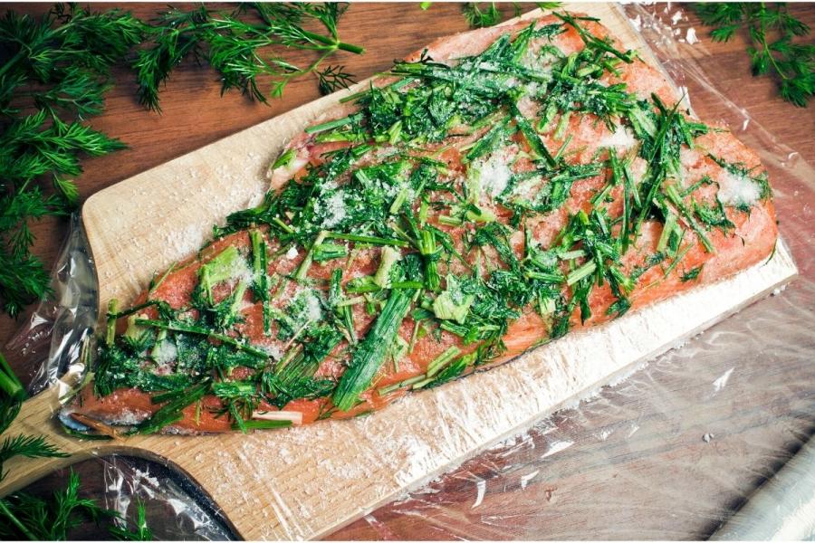 Salmón cubierto de sal, azúcar y eneldo, preparado para convertirse en gravlax.