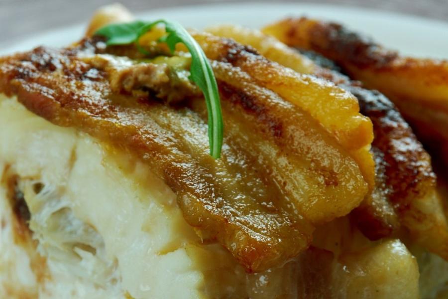Detalle de bacalao hecho en el horno con tocino ahumado.