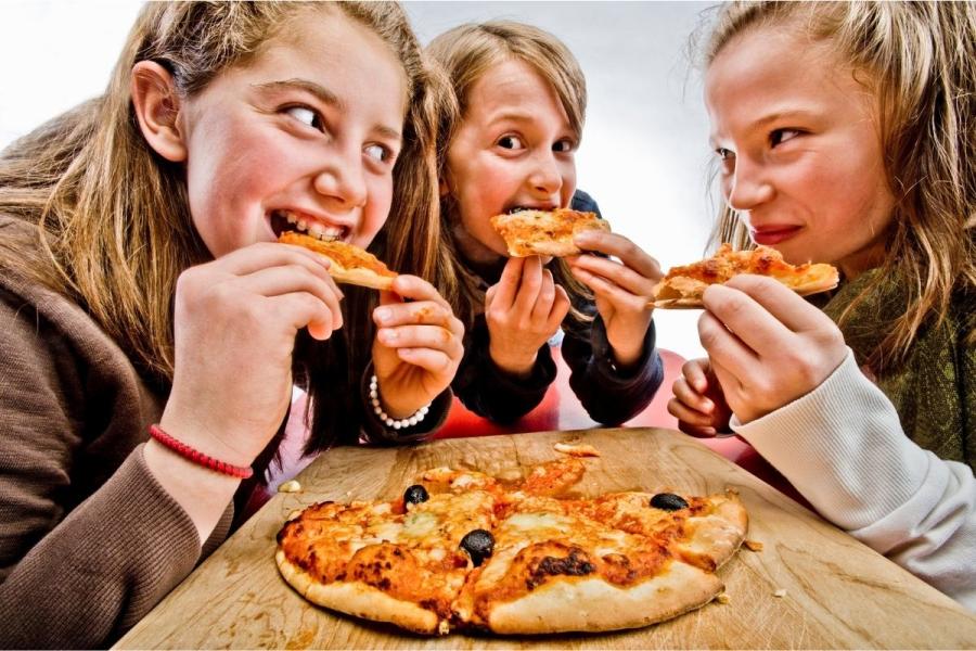 Adolescentes comiendo pizza casera.