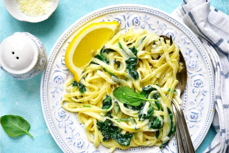 Un plato de pasta con espinacas y limón