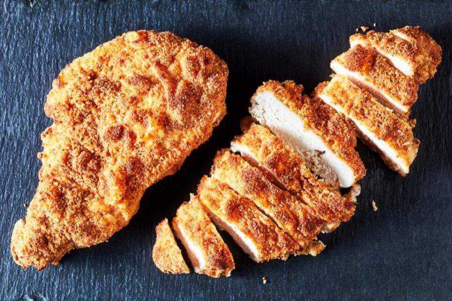 Pechugas de pollo rebozadas, una entera y una cortada.