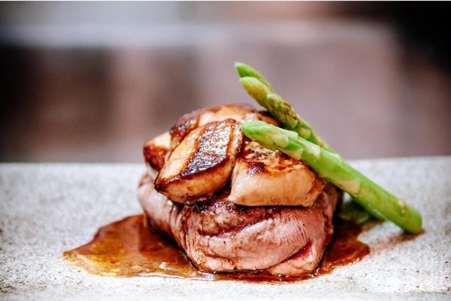 Solomillo con foie gras a la plancha, salsa y guarnición de espárragos.