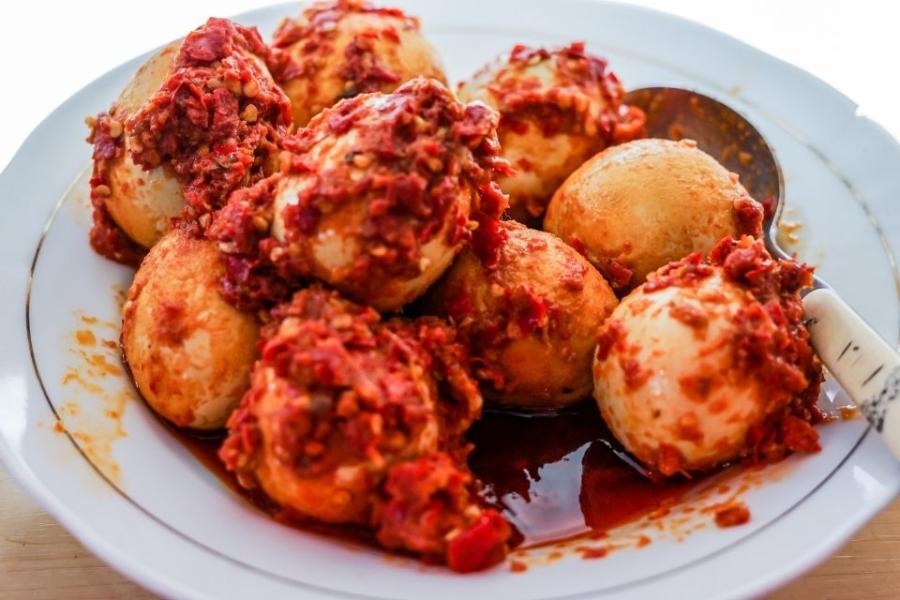 Huevos duros pelados y salsa balado en un plato.