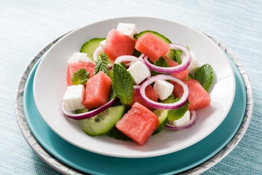Ensalada de sandía con menta servida en un plato de loza.