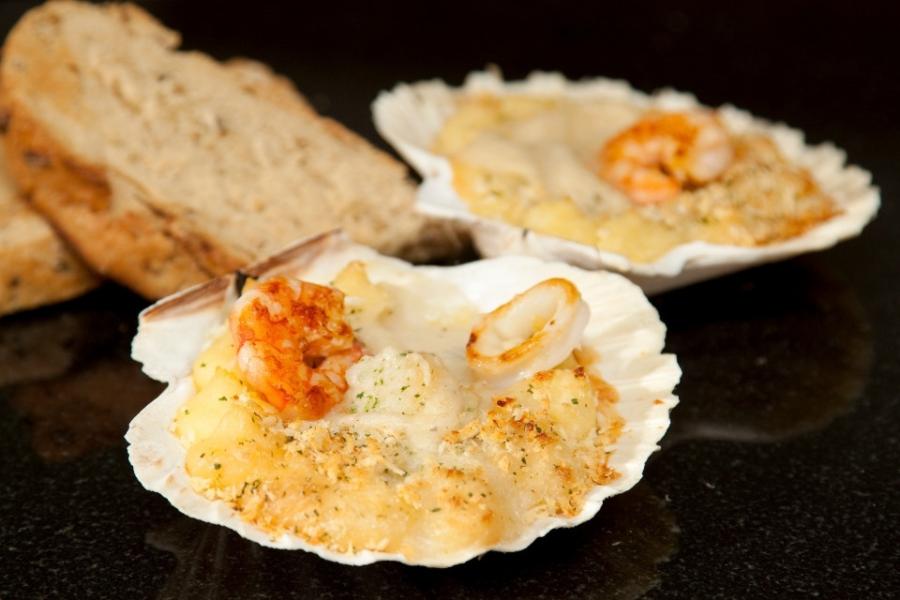Pescado y marisco gratinados en conchas de vieira.