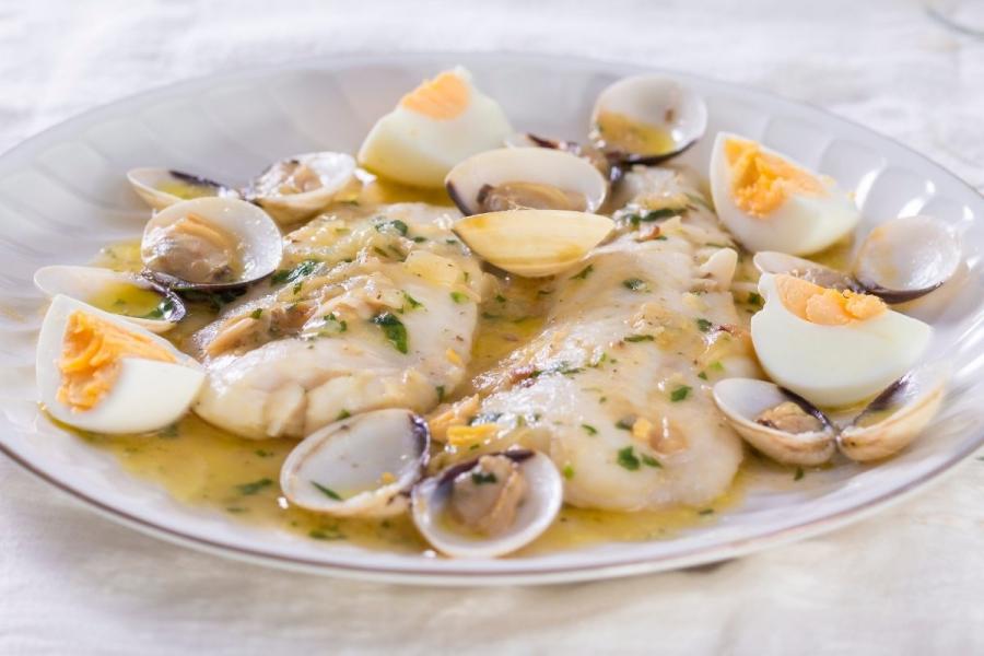 Merluza a la cosquera, o merluza koxkera, guisada con almejas.