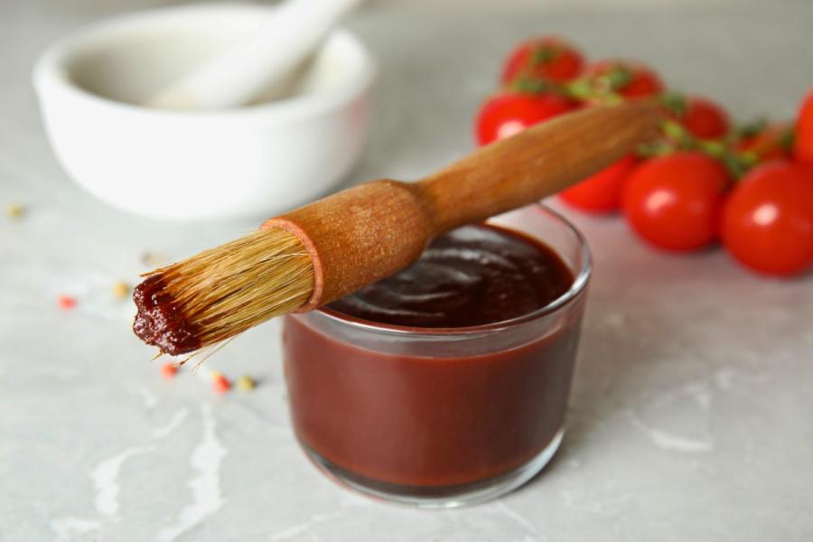 Salsa barbacoa en un recipiente de vidrio con un pincel para untarla colocado sobre el recipiente.