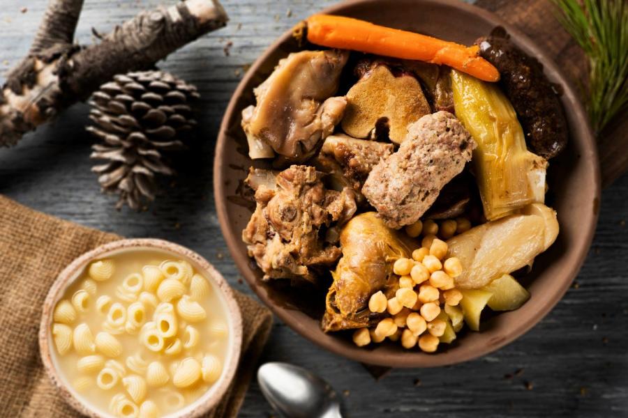 Presentación de una escudella y carn d´olla catalán con sopa de pasta y las verduras y diferentes tipos de carne al lado.