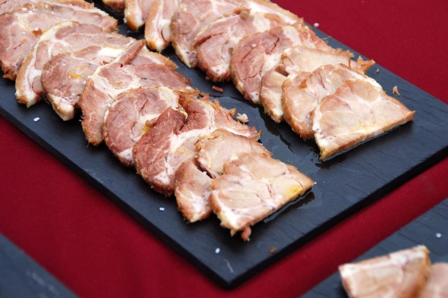 Una tabla de pizarra con lonchas de carne de cerdo mechada en fiambre.