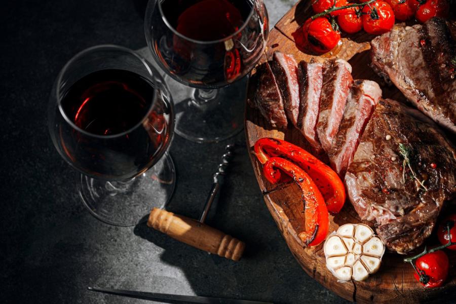 Comida para dos con filetes y vino tinto.