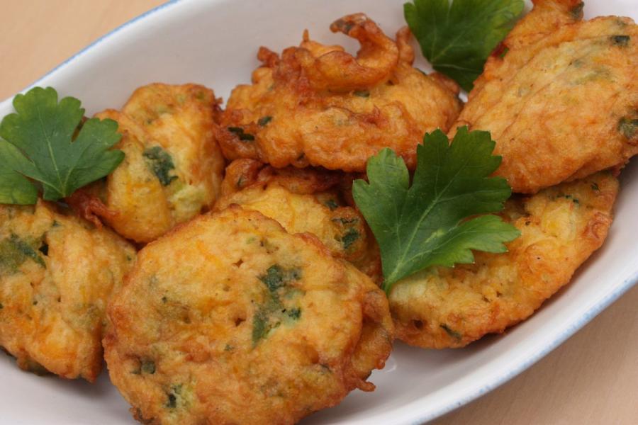 Buñuelos de calabacín bien dorados, decorados con perejil
