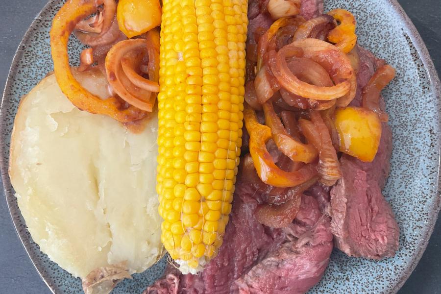 Lonchas de filete de vaca a la barbacoa con una salsa hecha del adobo, acompañado de maíz y patata asados.