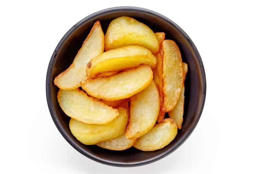 Un cuenco con patatas fritas en forma de cuña gruesa.