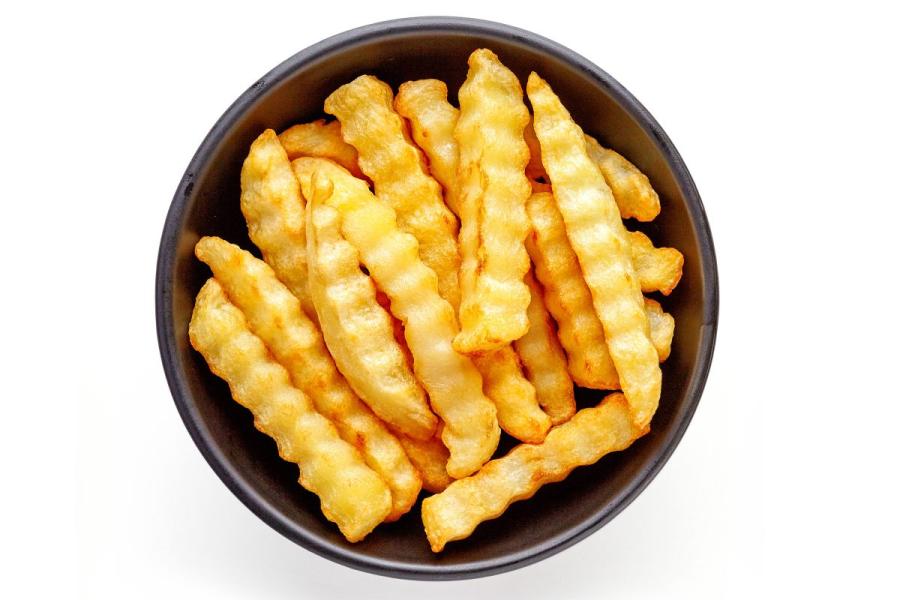 Un cuenco con patatas fritas cortadas en forma de varitas onduladas.
