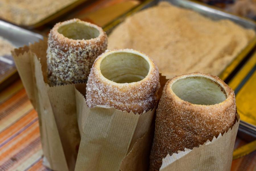 Pasteles chimenea húngaros, dulces cilíndricos de masa enrollada y horneada sobre un palo, cubiertos de azúcar y a veces canela, nueces y otros ingredientes.