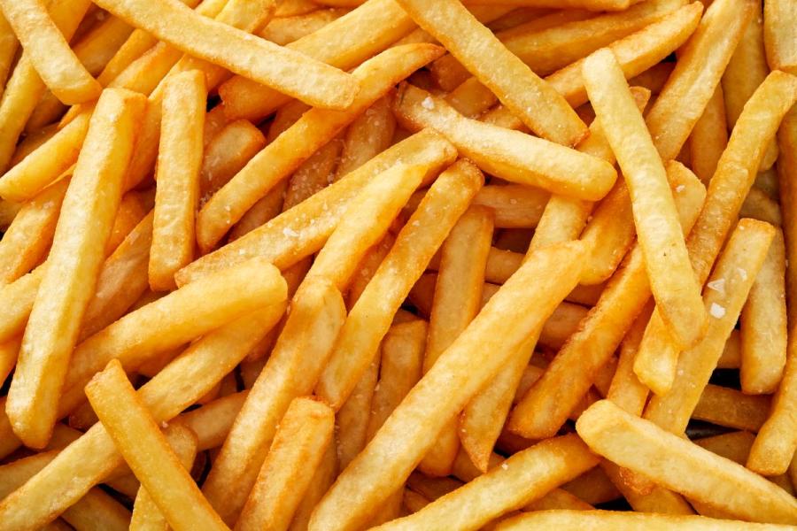 Detalle de patatas fritas clásicas, cortadas en bastoncitos, fritas congeladas..
