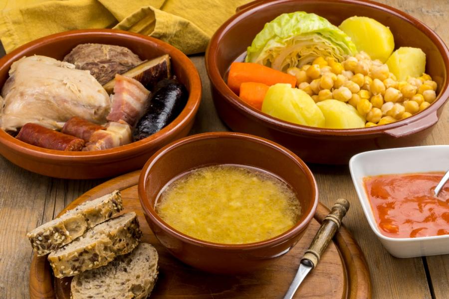 Un cocido madrileño completo. con su sopa, verduras, garbanzos y carnes.
