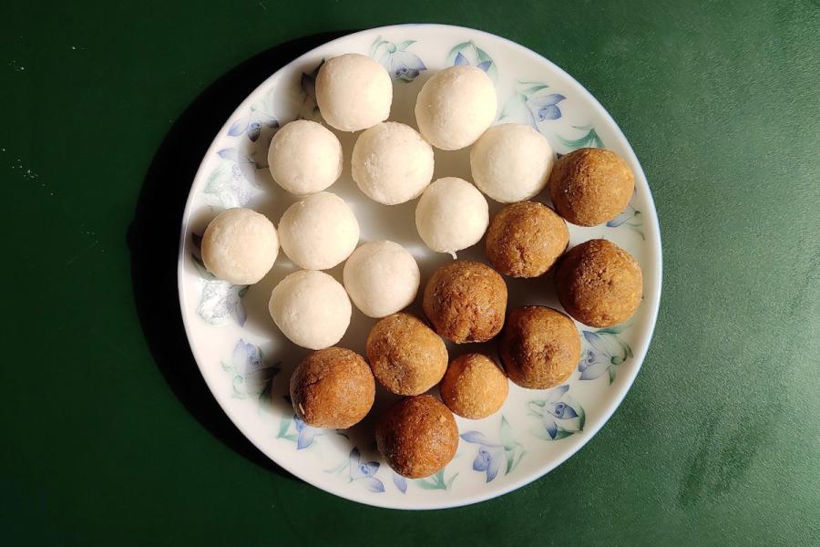 Un plato con bolitas de coco, narikol laru, hachas con azúcar blanco y azúcar moreno.
