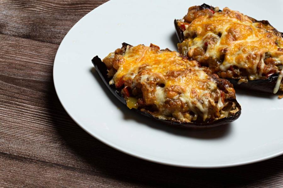 Berenjenas rellenas de carne y verduras gratinadas con queso rallado.
