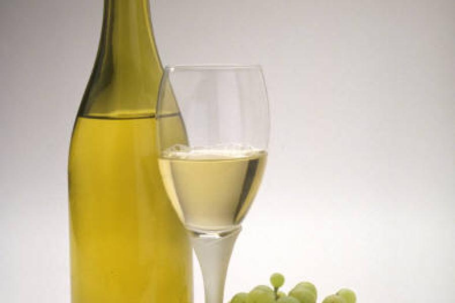 Una botella de vino blanco y uvas.