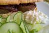 Bocadillo de morcilla con rodajas de pepino y coleslaw.
